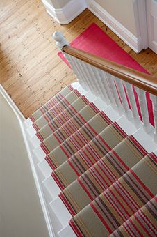 an overhead view of a stair case with red and beige striped rugs on it