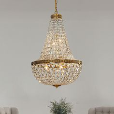 a chandelier hanging from the ceiling in a living room with two chairs and a table