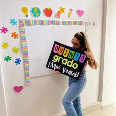 a woman holding a sign in front of a whiteboard that says quino grad nui namest