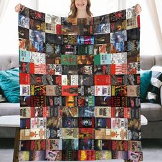 a woman standing in front of a couch holding up a blanket made out of books