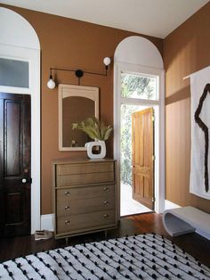 a room with a dresser, mirror and rug in it