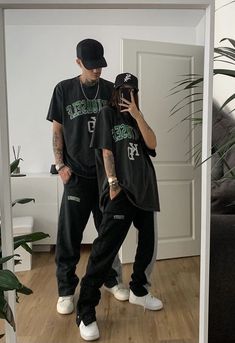 two people standing in front of a mirror with one holding a cell phone and the other taking a selfie