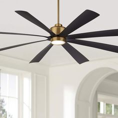 a ceiling fan with four black blades hanging from it's center point in an empty room