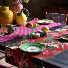 the table is set with plates, cups and vases