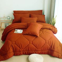 an orange comforter and pillows on a bed in a room with a white floor