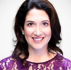 a woman wearing a purple lace dress smiling at the camera with her eyes wide open