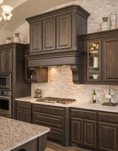 a kitchen with brown cabinets and marble counter tops