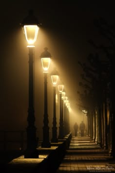 a row of street lamps sitting next to each other on a sidewalk in the dark