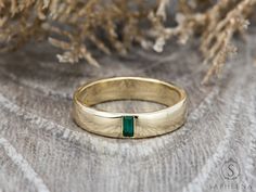 a close up of a gold ring with a green stone in the center on a table