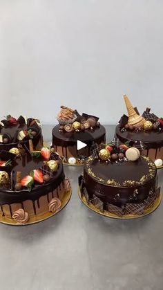 four cakes with chocolate frosting and strawberries on them