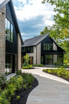 a large house with lots of windows and plants in the front yard, along with a walkway leading to it