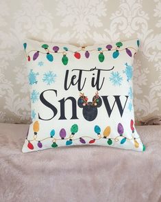 a pillow that has the words let it snow on it and christmas lights around it