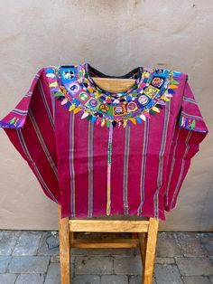 a colorful shirt is sitting on a small wooden chair in front of a stucco wall