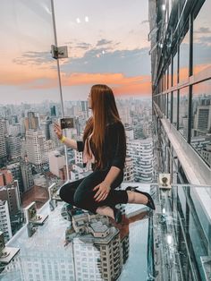 a woman sitting on top of a tall building