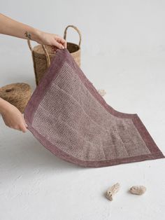 a woman is holding a piece of cloth in front of a basket with rocks on the floor