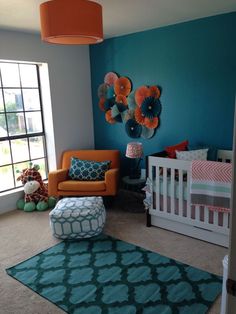 a baby's room with blue walls, orange and white furniture and rugs