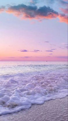 an ocean beach with waves coming in to the shore and clouds above it at sunset