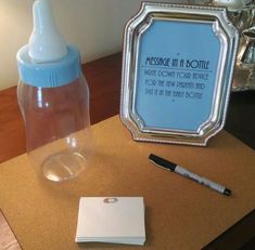 a baby bottle with a notepad and pen next to it on top of a table