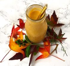 a glass jar filled with liquid sitting on top of leaves next to a pile of autumn leaves