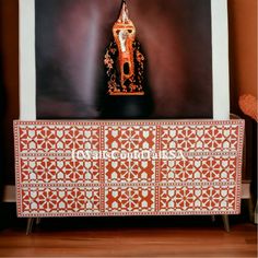 an orange and white cabinet with a gold buddha statue on it's sideboard