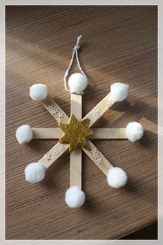 a snowflake ornament made out of popsicle sticks and cotton balls