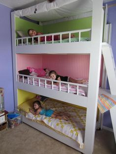 two children laying on top of bunk beds in a room with purple walls and carpet