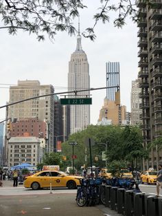 a yellow taxi is stopped at an intersection in new york city, with the empire building in the background