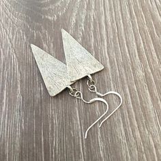 These modern triangle earrings are perfect for any outfit!  Silver fish hooks featuring a large textured silver triangle dangle and measuring a little over 2 inches in length.  Modern, minimalist, very cool. Item is carefully packaged and shipped via USPS in a sturdy protective mailer. Check out more fabulous jewelry and enter my shop here: https://www.etsy.com/shop/jewelbytessyla View the positive feedback I've received from customers and check out some beautiful art prints for nursery and home Triangle Earrings Dangle, Tropical Accessories, Big Pearl Necklace, Earrings Cool, Triangle Jewelry, Cool Earrings, Tropical Jewelry, Wood Bead Necklace, Fish Hooks