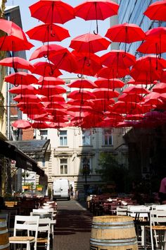 many red umbrellas are hanging above tables and chairs