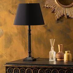 a black lamp sitting on top of a wooden table next to a mirror and vase