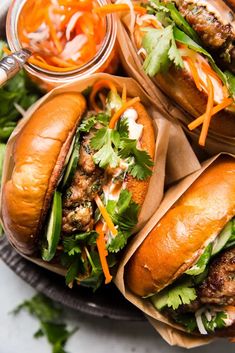 three sandwiches with meat, lettuce and carrots on a plate next to some dipping sauce