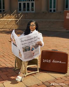 a woman sitting on a chair with a newspaper in front of her and a suit case