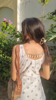 the back of a woman's head wearing a white dress and carrying a brown purse