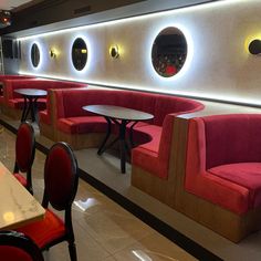 an empty restaurant with red booths and round mirrors on the wall above them, along with tables and chairs