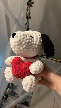 a hand holding a white and black dog with a red heart