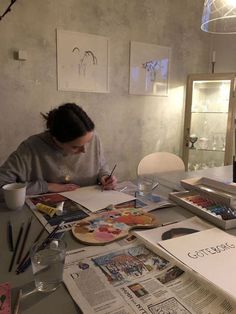 a woman sitting at a table with papers and pens