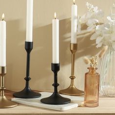 three candles are sitting on a shelf next to a vase with white flowers in it