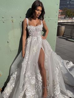 a woman in a white wedding dress leaning against a wall with her leg on the ground