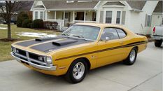 a yellow and black muscle car parked in front of a house