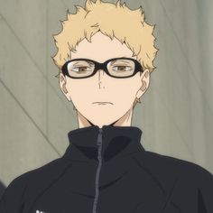 a man with glasses and blonde hair wearing a black hoodie looking at the camera