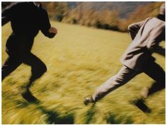 two men in suits are running through the grass