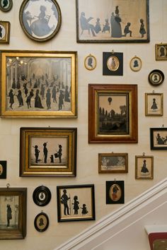 the wall is covered with many framed pictures and family silhouettes, including children's portraits