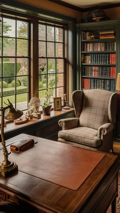 a chair and desk in front of large windows with bookshelves on either side