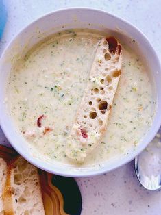 a white bowl filled with soup next to two pieces of bread on top of a table