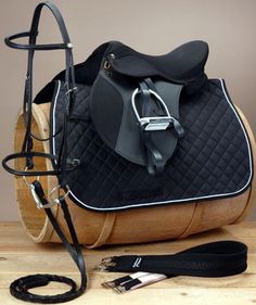 a horse saddle and bridle sitting on top of a wooden table