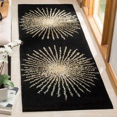 two black rugs with white and gold designs on them in a living room area