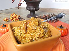 a yellow bowl filled with granola sitting on top of a table next to a vase