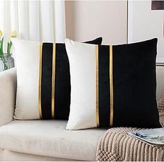 two black and white pillows sitting on top of a couch next to a vase with flowers