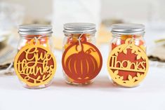 three mason jars filled with pumpkins sitting on top of a table