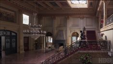 a man is walking down the stairs in an old building with chandeliers on either side